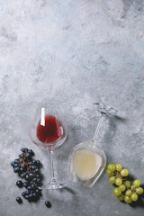 Traditional New european low alcohol red and white wine Federweisser or Neuer Wein, Burcak, Vin bourru in lying glasses with black and green grapes over grey concrete background. Flat lay, copy space