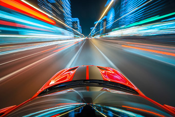 View from roof of the red muscle car Car moving in a night city, Blured road with lights with car on high speed. Concept rapid rhythm of a modern city.