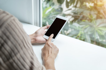 Close-up view of woman hands holding smartphone on white table. Using Technology Concept.