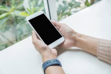 Close-up view of woman hands holding smartphone on white table. Using Technology Concept.