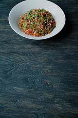 Asian cuisine. Cellophane noodles with crab sticks, vegetables and herbs. Funchoza. Proper nutrition. Healthy food. View from above. Dark wooden background. Space for text.