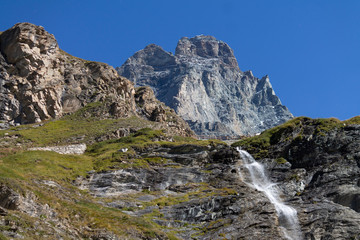 Fototapeta na wymiar Behind the waterfall there is the Matterhorn