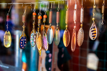 Multicolored rotating lures hanging in the window of a fishing shop.