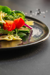 italian pasta salad farfalle, vegetables, mix leaves (tomato, cucumber, onion, lettuce, chard, arugula and more) menu concept. food background. copy space. Top view
