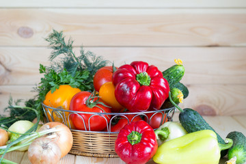 Vegetables harvest in wicker basket on wooden background. Natural organic homegrown products.