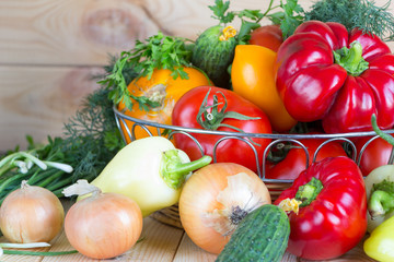 Close up vegetables harvest in wicker basket on wooden background. Raw foods.
