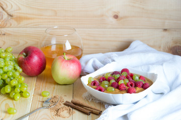 Raw food diet breakfast. Vegan flax porridge with raspberry and grape raisins in white bowl on linen fabric.