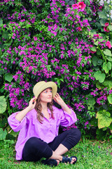 Girl sitting next to a tree with beautiful violet flowers