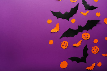 Halloween background with paper pumpkins, Jack O'Lantern, black, orange paper bats flying over purple background, . Copy space. Halloween and decoration concept.