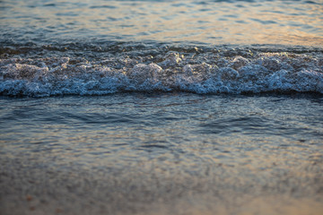 Shiny sea waves on the beach sand in sunset light