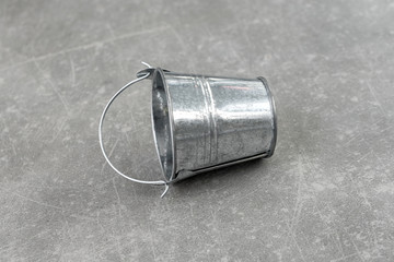 Empty small metal bucket isolated on a concrete background. Copy space. Horizontal view.