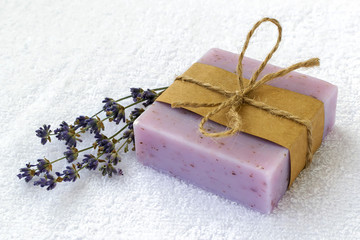 Soap bar with dry aromatic lavender flowers. Purple handmade soap on a white terry cotton towel. Natural toiletries and hygiene products with herbs and essential oils.