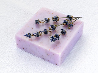 Handmade soap bar with dry aromatic lavender flowers. Purple  soap on a white terry cotton towel....