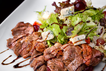 Warm salad with meat and cheese on a white plate