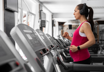 Fototapeta premium Beautiful young pregnant woman is working out in the gym