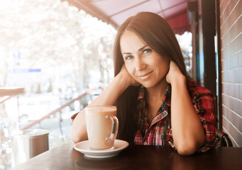 Beautiful woman with long hair drinks coffee outdoors.
