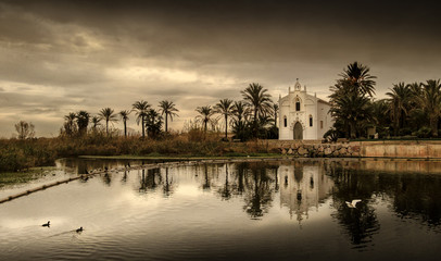 Ermita cristiana junto a orilla río albufera en atardecer dorado