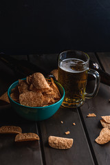Set of french fries on the wooden table with glass of beer and black background
