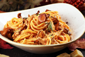 pasta with organic chanterelles. portion of spaghetti pasta with fried chanterelles in a creamy garlic sauce with cheese on a table