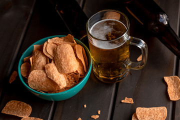 Set of french fries on the wooden table with glass of beer and black background