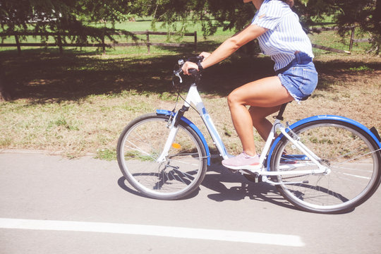 Pretty Young Woman Riding Bicycle In The Park Rear View