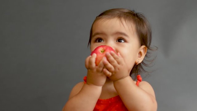 girl child in a red t-shirt eating a red apple