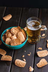 Set of french fries on the wooden table with glass of beer and black background