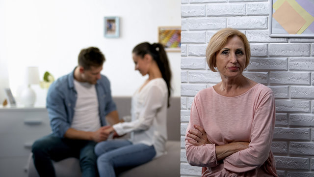 Jealousy, dissatisfied mother-in-law watching young couple flirting at home