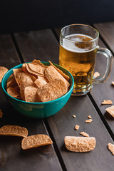 Set of french fries on the wooden table with glass of beer and black background