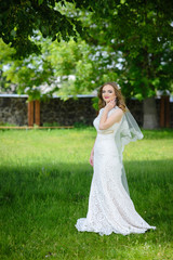Full length photo of conceived blonde bride in a white dress in the summer park