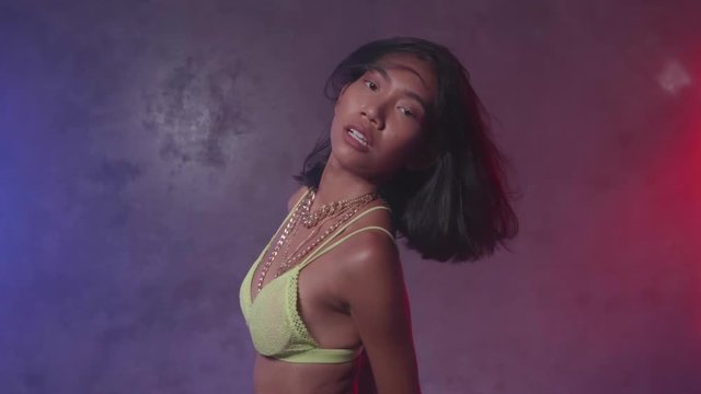 Portrait of young beautiful woman dancing in studio with neon lights - video in slow motion