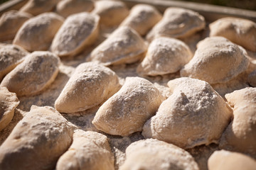 Fototapeta na wymiar Raw dumplings on a wooden board. Slavic traditional dish. Dough for dumplings.