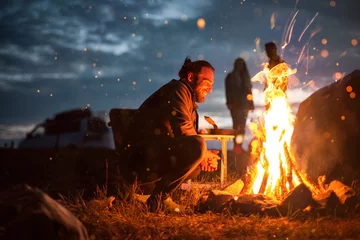 Foto auf Acrylglas Camping Lächelnder Mann neben einem Lagerfeuer im Dunkeln