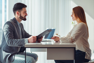 Nervous woman looking at manager reading her resume during a job interview at office