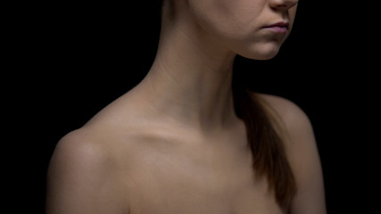 Naked female standing against black background, fighting insecurities concept