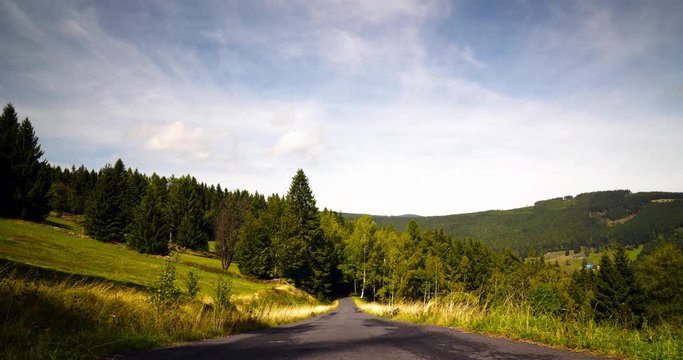 Timelapse of wooden landscape with mountains, hills and road and blue cloudy sky in Krkonose (Giant Mountains), Czech Republic