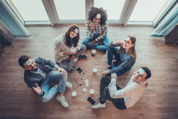 Cheerful friends playing game with sticky notes in the office