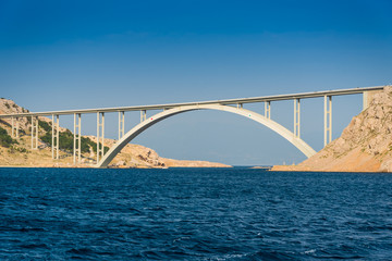 Obraz premium Bridge to the island Krk under blue sky on a sunny summer day. Krk is the big island of the Croatian coast of the Adriatic Sea. Travel landscape