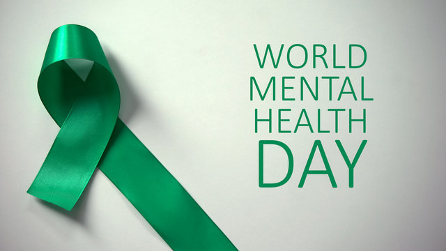 World mental health day inscription, green ribbon on table, awareness campaign
