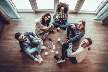 Group of young people in office floor having fun playing name game with sticky notes to their...
