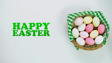 Happy Easter text basket with colored eggs lying on white background, bunny ears