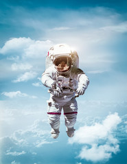 Astronaut floating in stratosphere of planet Earth. CLouds and blue sky on background. Under space....