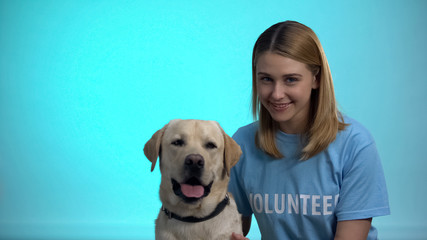 Smiling female volunteer with cute pedigreed dog looking at camera, help animals