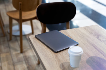 A dark laptop on the light wood table