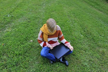 Naklejka na ściany i meble young woman lies on grass with laptop