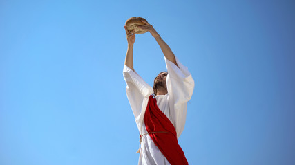 Jesus God raising bread in hands to sky, blessing sacramental food, Eucharist