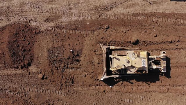 Bulldozer pushing large amount of fresh soil, Aerial follow footage.
