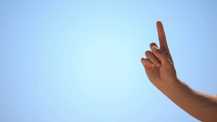 Male hand pointing finger up on sky background, concept of new idea, wise advice