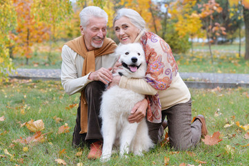 Portrait of happy senior couple in autumn park with dog