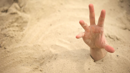 Hand sinking in quicksand, trying to get out, tips to survive in desert, buried